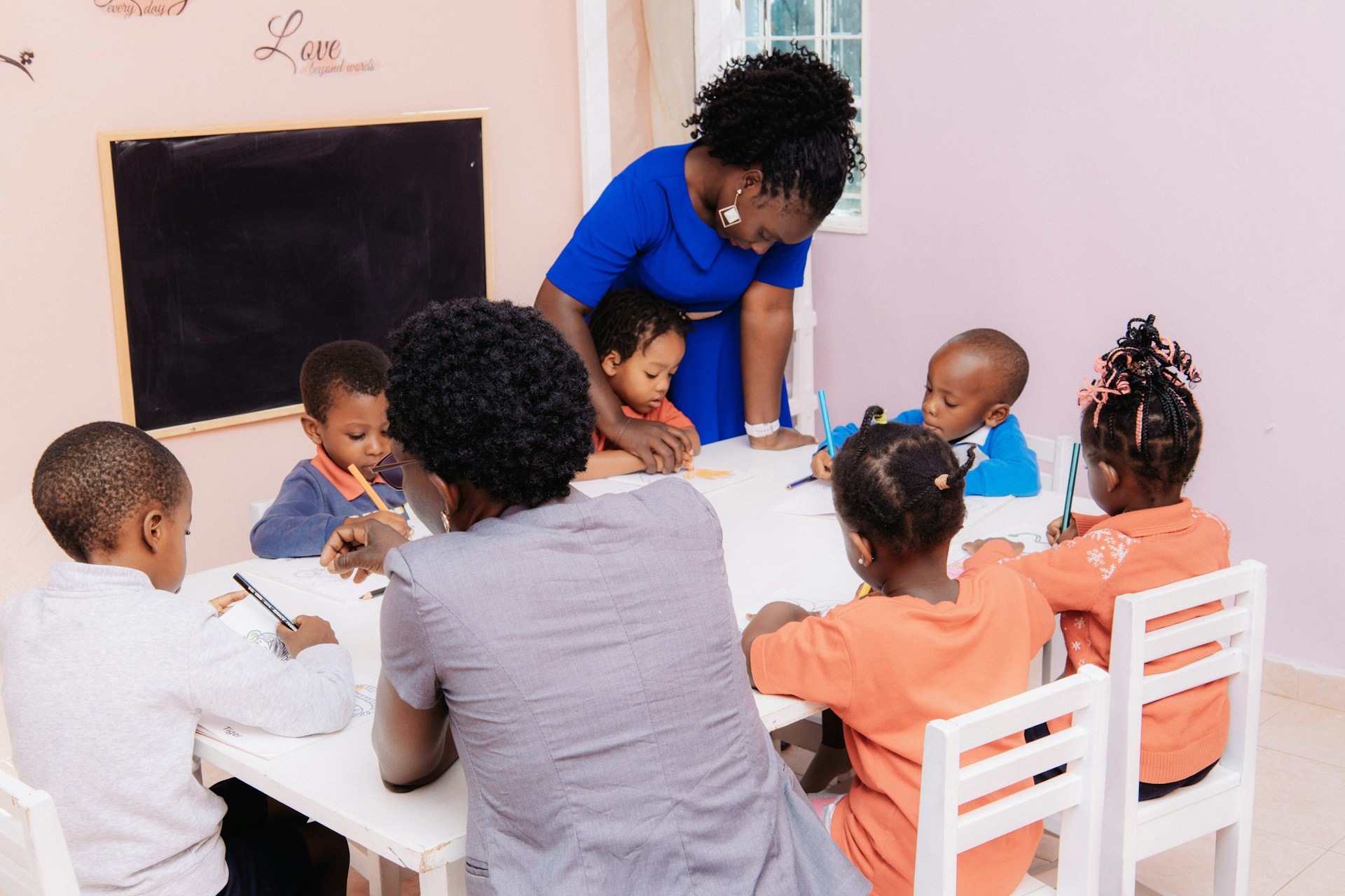 Teacher guiding children in a Ugandan classroom